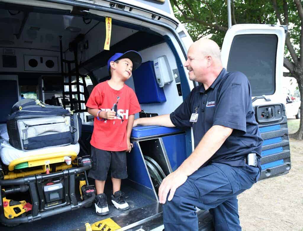 Photo - Lance Hoffrage of Pistoresi Ambulance shows Omar Rojas, 4, what the inside of an ambulance looks like during the 2017 National Night Out at Madera District Fairgrounds.