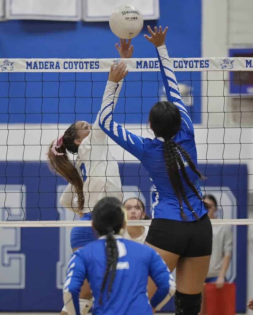Photo - Madera’s Jania Warren gets a kill attempt past the block of Caruthers in Tuesday’s five-set loss. Warren led the Coyotes with 13 kills. 