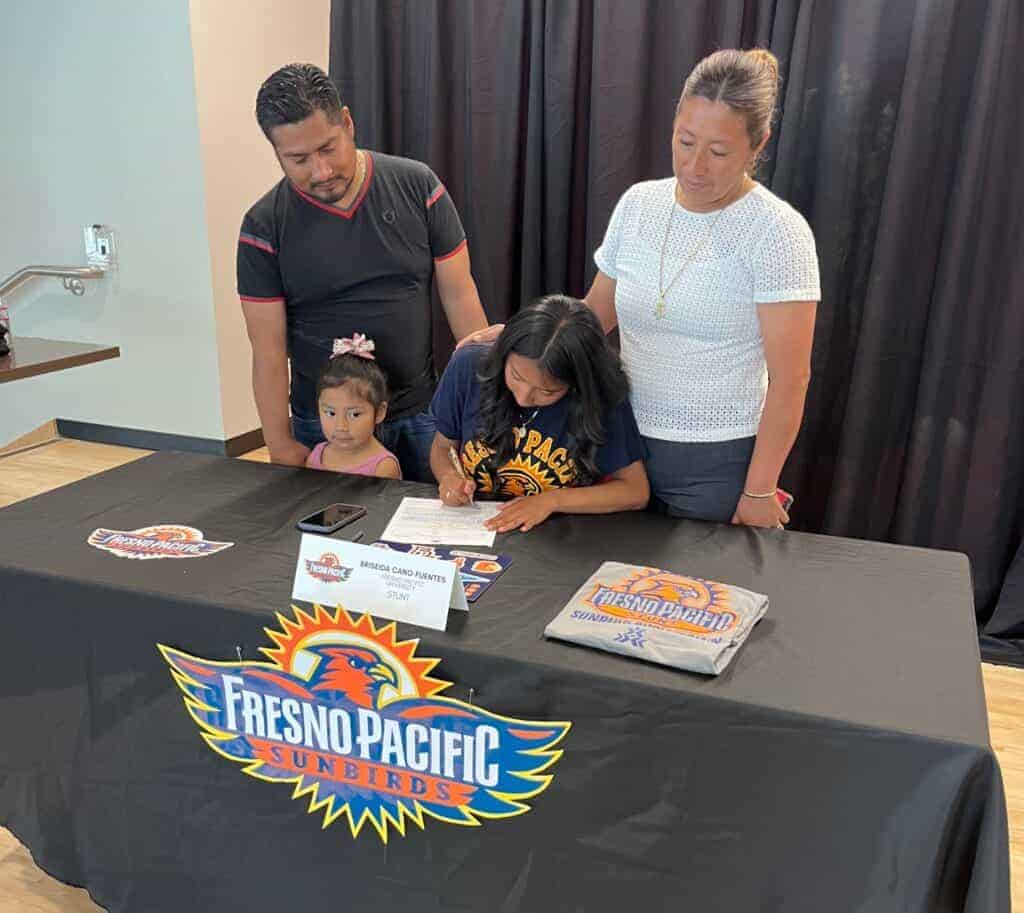 Photo - Matilda Torres’ Briseida Cano-Fuentes signs her National Letter of Intent to participate in Competitive Sport Cheer (Stunt) at Fresno Pacific University with her parents and sister watching during a signing ceremony at the Torres Cafeteria in June.