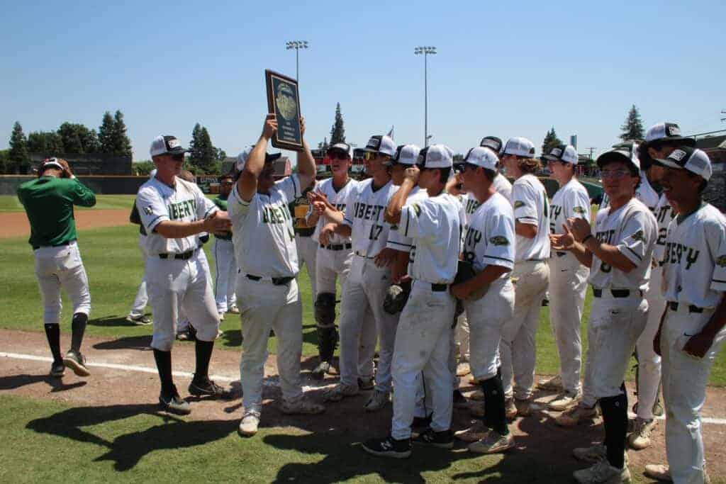 Photo - Liberty senior Dylan Whiteman holds up the Central Section Div. IV Championship plaque to his team after Saturday’s 9-5 victory over Immanuel in Visalia’s Valley Strong Ballpark.