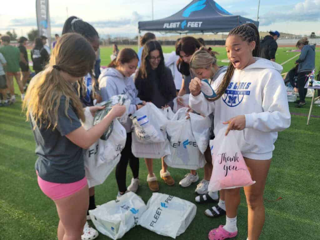 Photo - A group of Madera Coyote track athletes are excited by what they received in their garment bags during Project Run Madera’s fourth annual giveaway that included shoes and socks for every track athlete at each of Madera Unified School District’s high schools and middle schools.