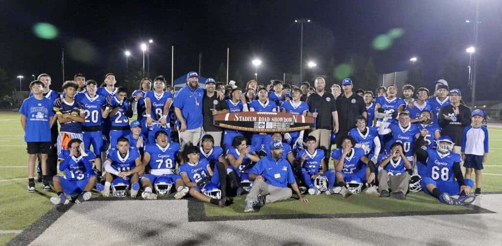 Photo - The Madera Coyotes football team celebrates with the bandsaw trophy after defeating the Madera South Stallions, 49-7, to win the Stadium Road Showdown for the 14th time in 17 contests.