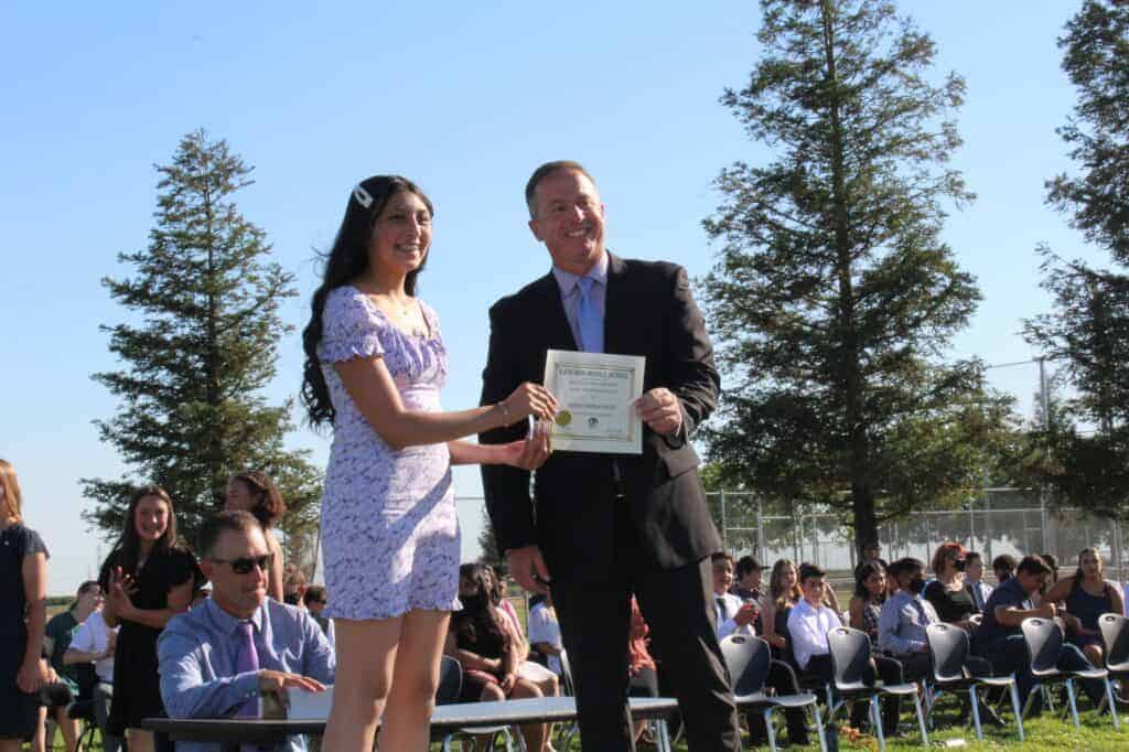 Photo - Ranchos Middle School principal Chris Imperatrice presents Denise Corona-Cortez with her certificate of promotion at the school’s promotion ceremony on June. 2.