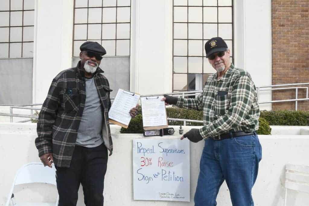 Photo - Derek Robinson, left, and Rick Farinelli, collect signatures Thursday outside the post office for a petition to repeal 30 percent raises for the Madera County supervisors.