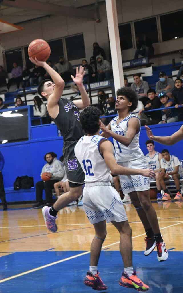 Photo - Madera South’s Lucas Samaniego drives the lane over Madera’s J’Sean Gonzalez to score two points durin the Stallions’ victory last Wednesday.