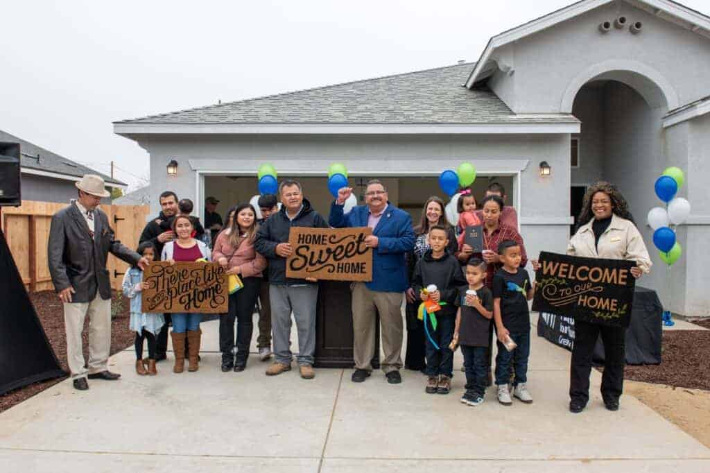 Photo - From left, Madera Mayor Pro-Tem Artemio Villegas, Madera Mayor Santos Garcia and City Council member Anita Evans help hold the welcome mats of the Garcia-Pizano, Robles and Cuellar-Anaya families after they received the keys for their Habitat for Humanity homes on Friday.