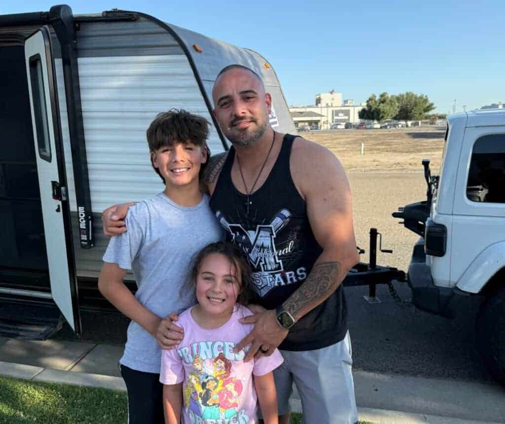 Photo - Dad Ozzy, son Leo and daughter Lila Barajas stand in front of their camper while waiting to purchase All About Dance recital tickets.
