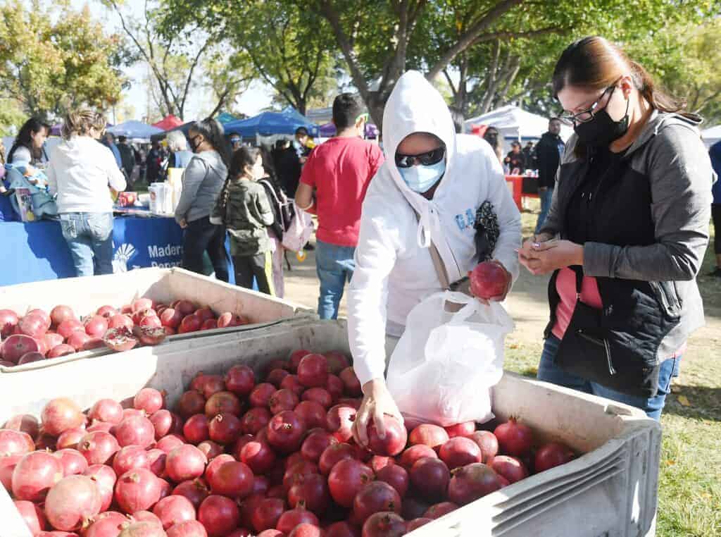 Photo - Maria and Carolina Gomez buy pomegranates during the 2021 Pomegranate, Fruit & Nut Festival hosted by the Madera Chamber of Commerce at the Madera District Fair. This year's event is on Saturday.