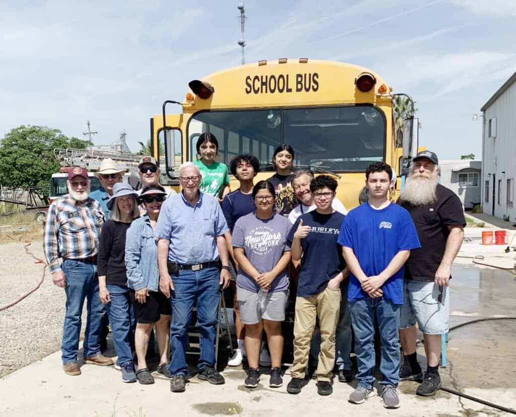 Photo - Madera Sunrise Rotary Club members and Madera Interact members gather by the bus purchased by the Interact members to be donated for use in Mexico.