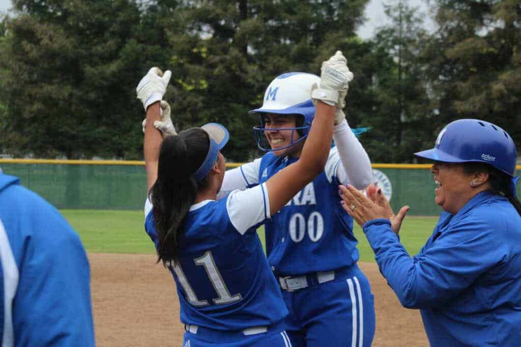Photo - Madera’s Jocelyn Mendez (00) celebrates with Erika Perez (11) and first base coach Melissa Armiento-van Loon after her ninth inning single drove in the game-inning run Monday against Liberty of Bakersfield.