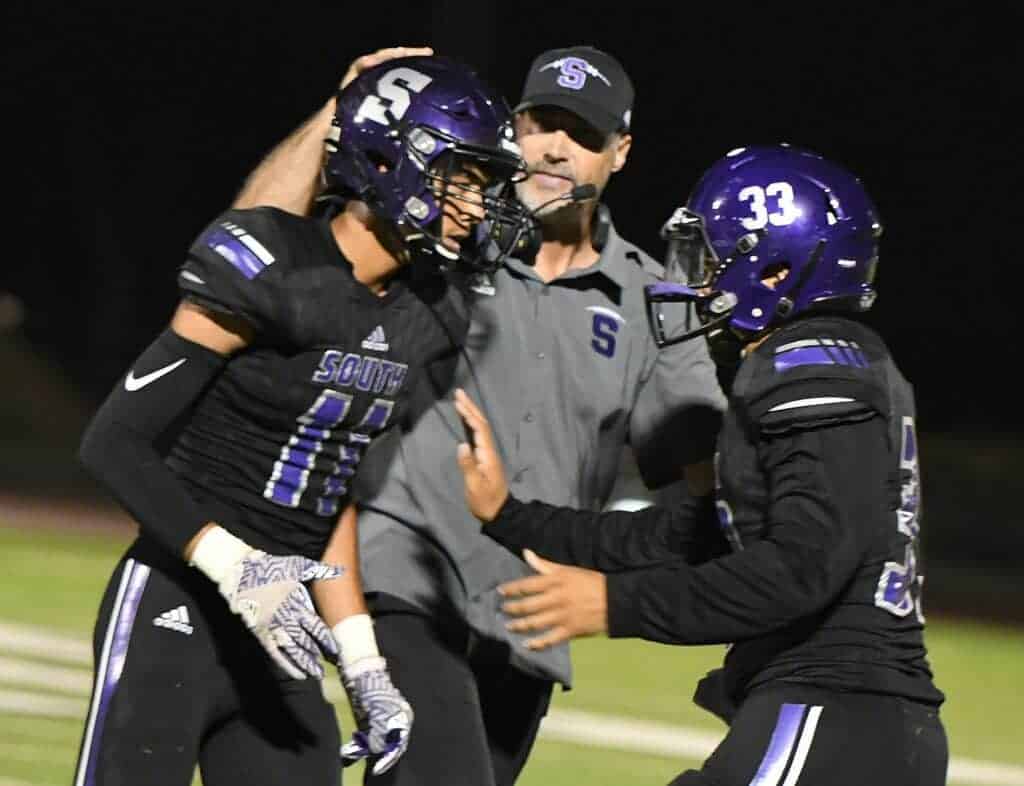 Photo - Madera South head coach Matt Johnson congratulates Jesse Ford (11) and Marvin Brewer (33) during a game last season. Johnson is recovering nicely after a dirtbike accident a couple of weeks ago.