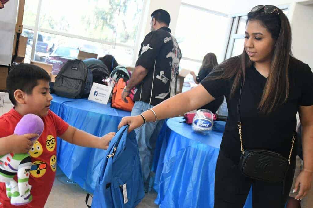 Photo - Aushpreet Brar of Madera Ford gives Omar Martinez a backpack during a distribution in 2019.