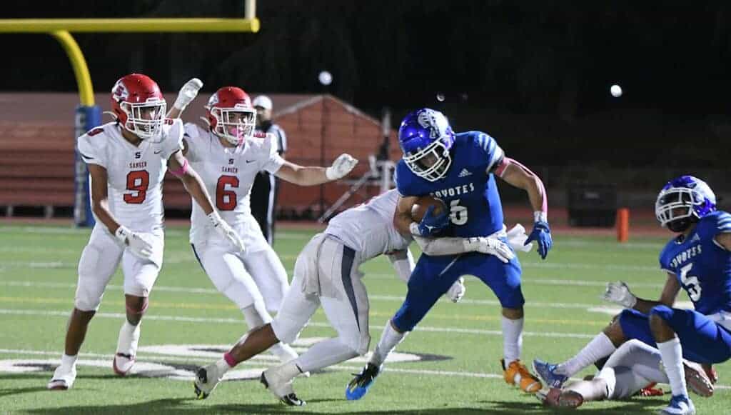 Photo - Madera’s Daniel Mendez tries to stay on his feet during one of his team-high 28 carries in Friday’s loss to Sanger.