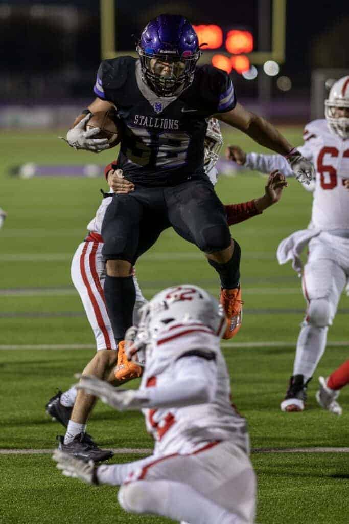 Photo - Madera South running back Erik Cervantes runs through a tackle and jumps over a defender during Friday’s Div. V playoff victory over Santa Maria.