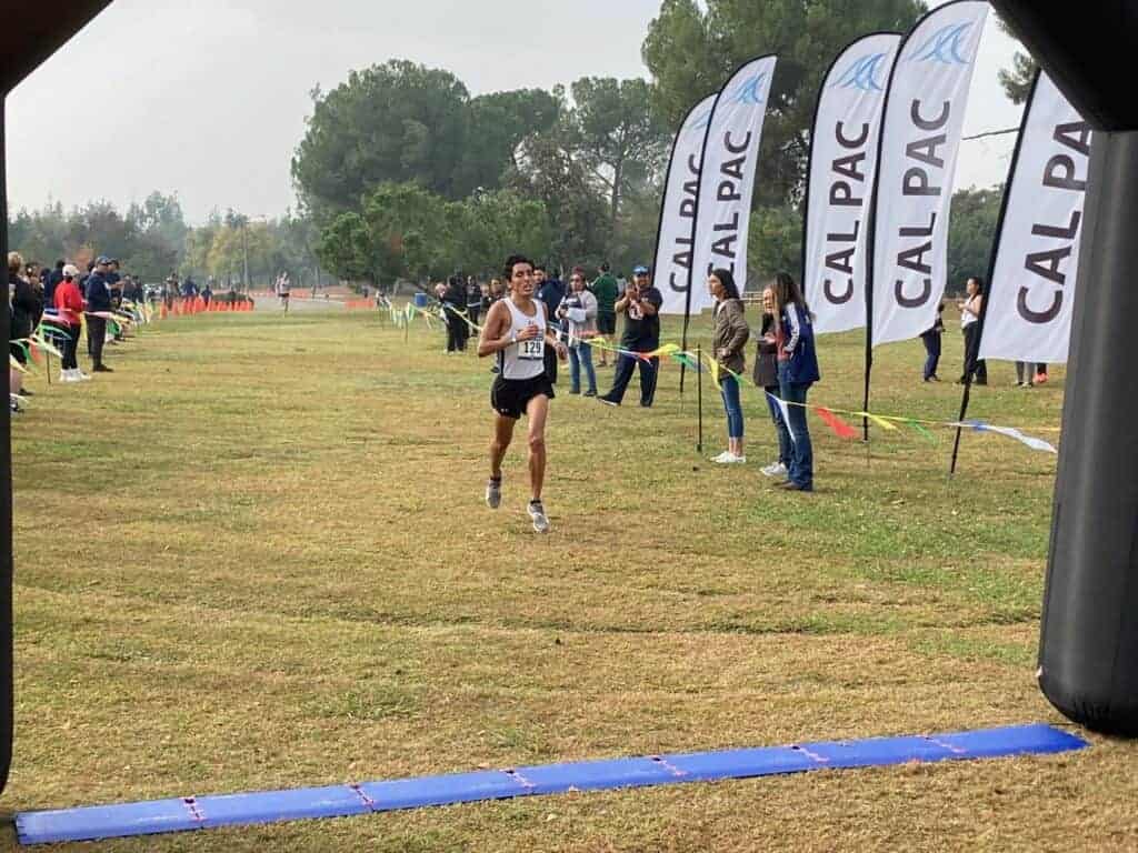 Photo - Former Madera South cross country runner Nicholas Hernandez crosses the finish line at the Cal Pac Cross Country Championships in second place to help lead Embry-Riddle to its eighth straight conference title Monday at Woodward Park.