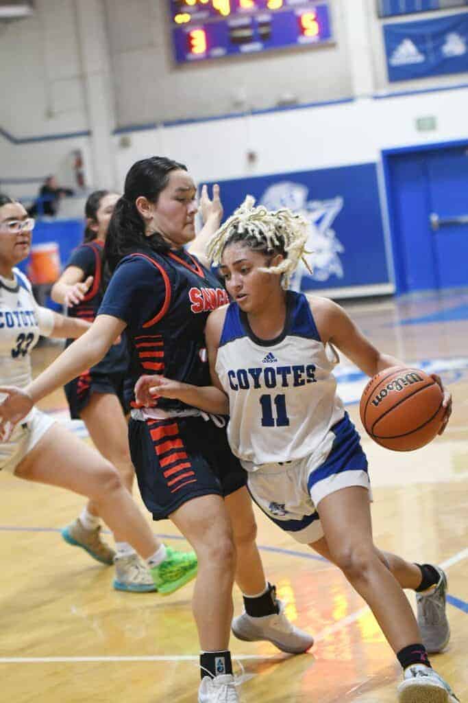 Photo - Madera’s Rhynne Mitchell tries to drive around Sanger’s Lucia Takeda during Wednesday’s loss to the Apaches. Mitchell led the Coyotes with 13 points and seven rebounds. 