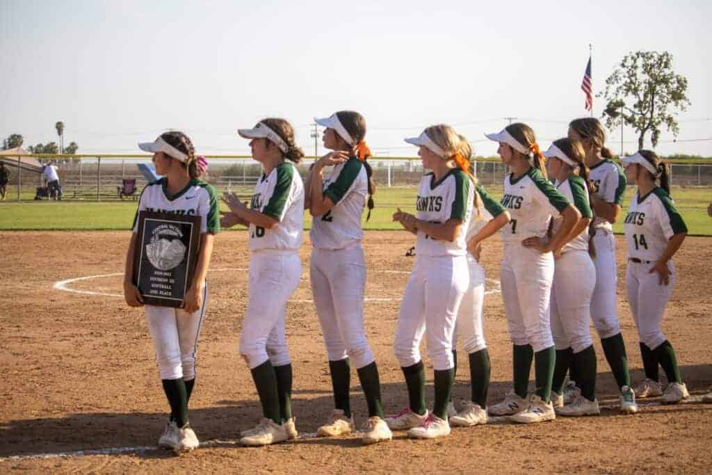 Photo - The Liberty softball team’s lone senior Jaclyn Smith holds the Div. III Central Section runner-up plaque while she and the rest of the team watches Tulare celebrate the section championship last Thursday after a 4-0 victory over the Hawks.