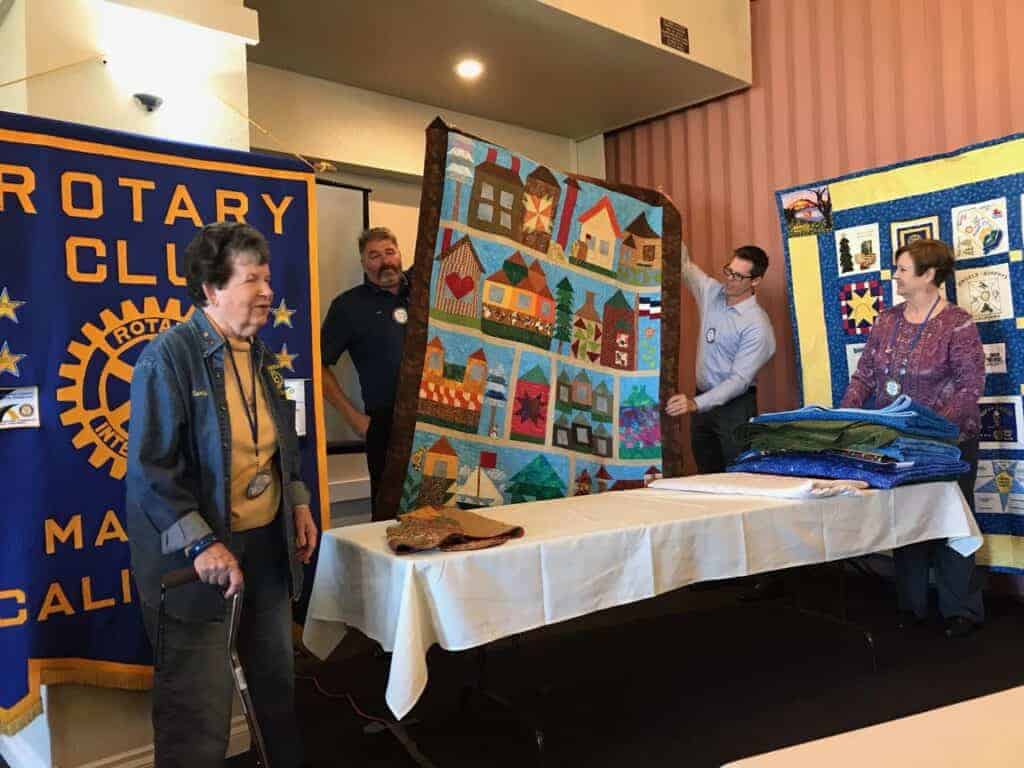 Photo - Heart of California Quilters’ Guild member Marty Wyatt, left, displays her handiwork on one of her many quilts at her Rotary Club meeting. Many examples of the guild members’ work will be on display March 2 and 3 at Hatfield Hall at the Madera District Fairgrounds.