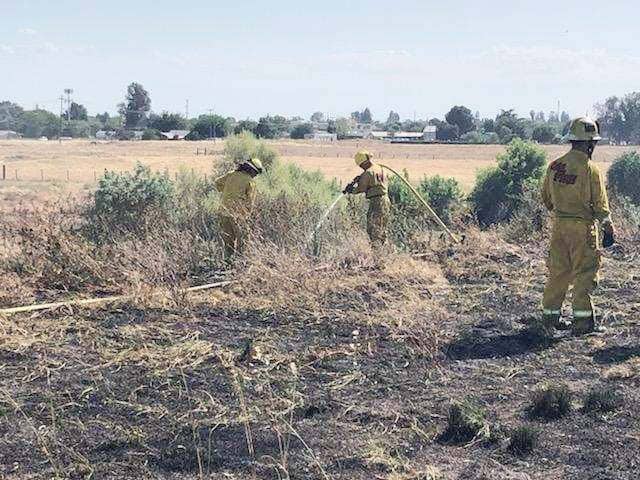 Photo - Fire crews battled two grass fires in the same riverbed area of homeless encampments on Raymond Road near Avenue 16 on Monday.