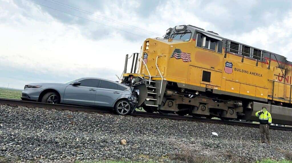 Photo - A Honda Accord sits in front of a train after it was pushed about a quarter of a mile. The Honda hit a big rig and settled on the tracks. The driver was able to exit the vehicle without injuries.