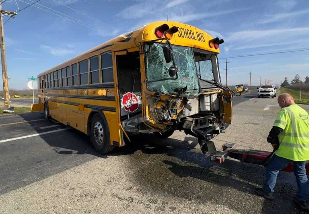 Photo - A Madera Unified School District bus is lifted on a tow truck following an accident on Avenue 12 and Road 26 on Friday.