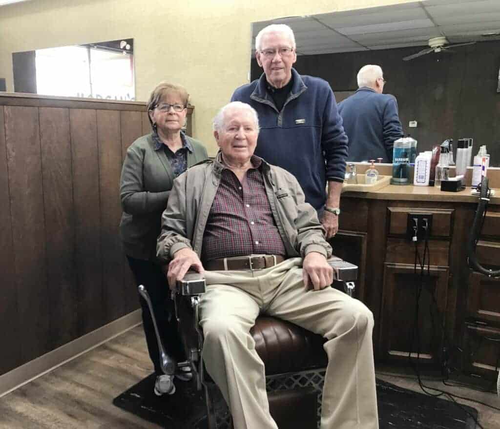 Photo - Gary Morgan (center), son of the original owner of Morgan’s Barber Shop, sits in one of the original barber chairs in a stall. Behind him are current owners, Jeanne and Robert Haley.