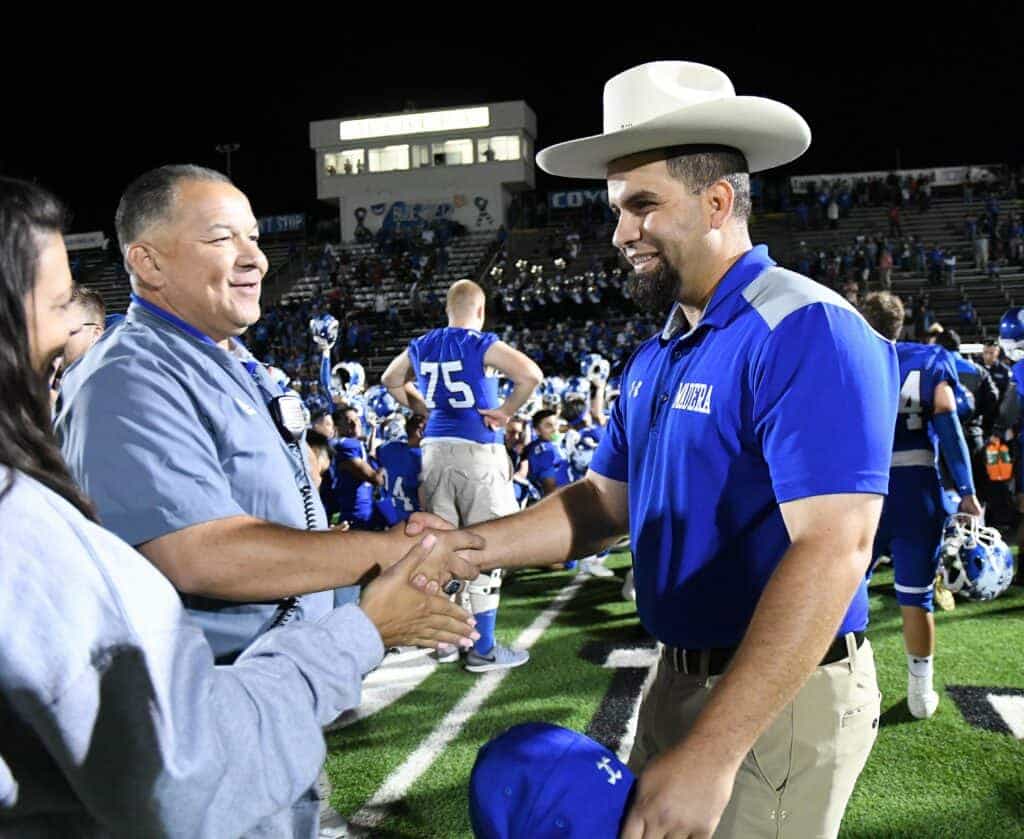 Photo - Madera Coyote head coach Yosef Fares wears the Governor’s Hat after his team defeated Merced 48-42 on Friday. He receives congratulations from Madera athletic director John Fernandez and principal Robyn Cosgrove.