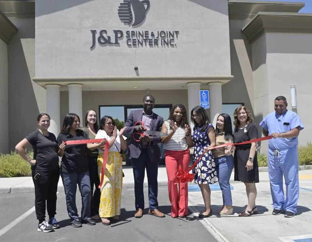 Photo - Justice Otchere MD, and his wife, Princess Otchere, NP, center, owners of J&P Spine & Joint Center Inc., are joined by staff and Madera Mayor Cece Gallegos, second from right, on Monday as they cut the ribbon for their new Madera location, 457 E. Almond Ave. Ste 105.