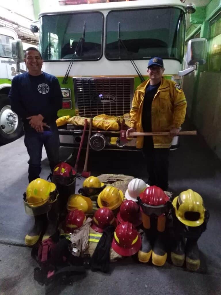Firefighters gear and helmets displayed in front of fire truck, highlighting emergency preparedness.