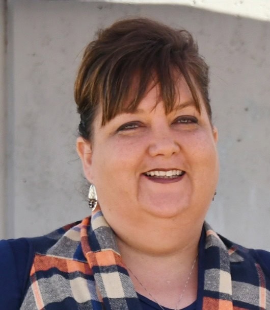 Portrait of a smiling woman in casual attire.