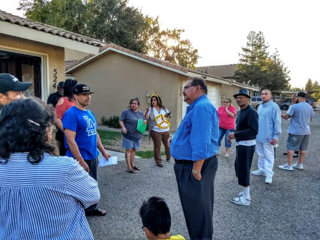 Community members gather outside a house for a local meeting in Madera.