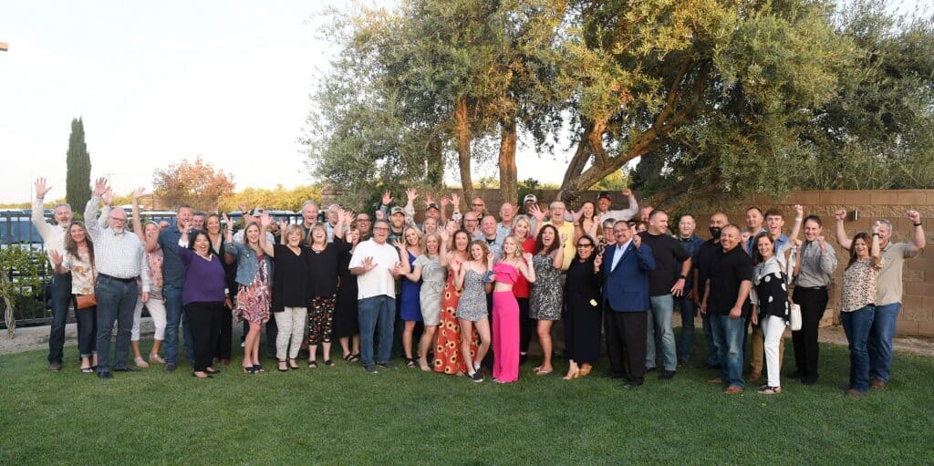 Group of diverse people celebrating together outdoors at The Madera Tribune event.