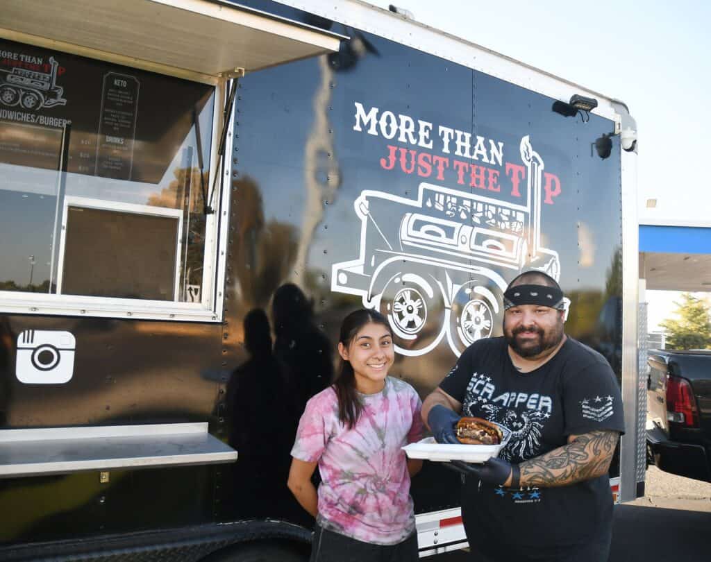 Food truck with "More Than Just the T" logo and two smiling customers.