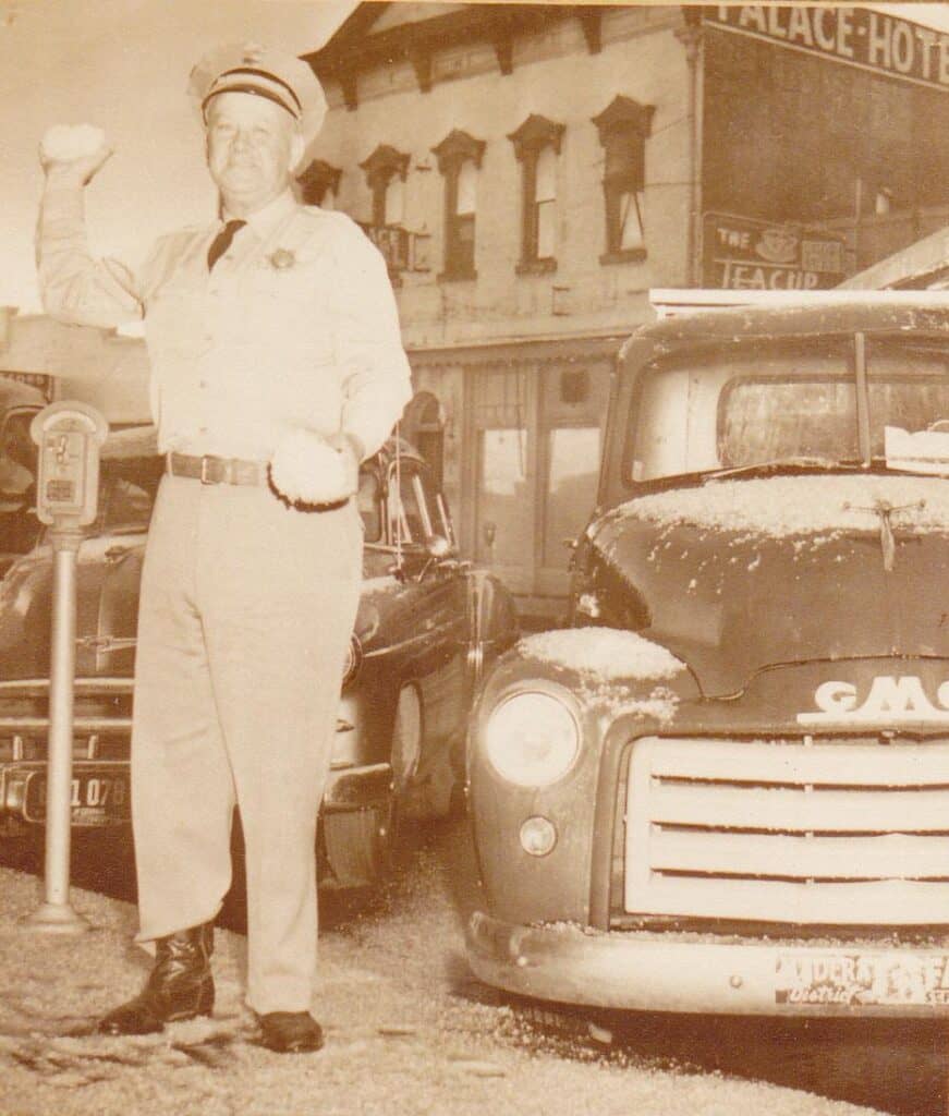 Vintage photo of a man standing next to an old truck in Madera.