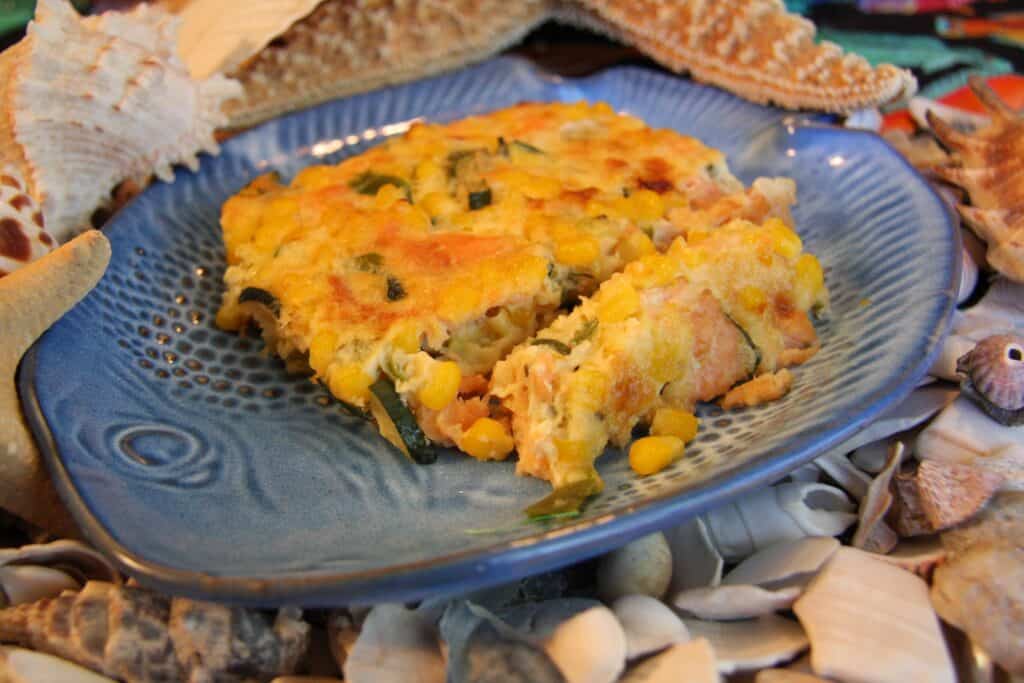 Seafood casserole on a blue plate with shells and starfish, highlighting local cuisine.