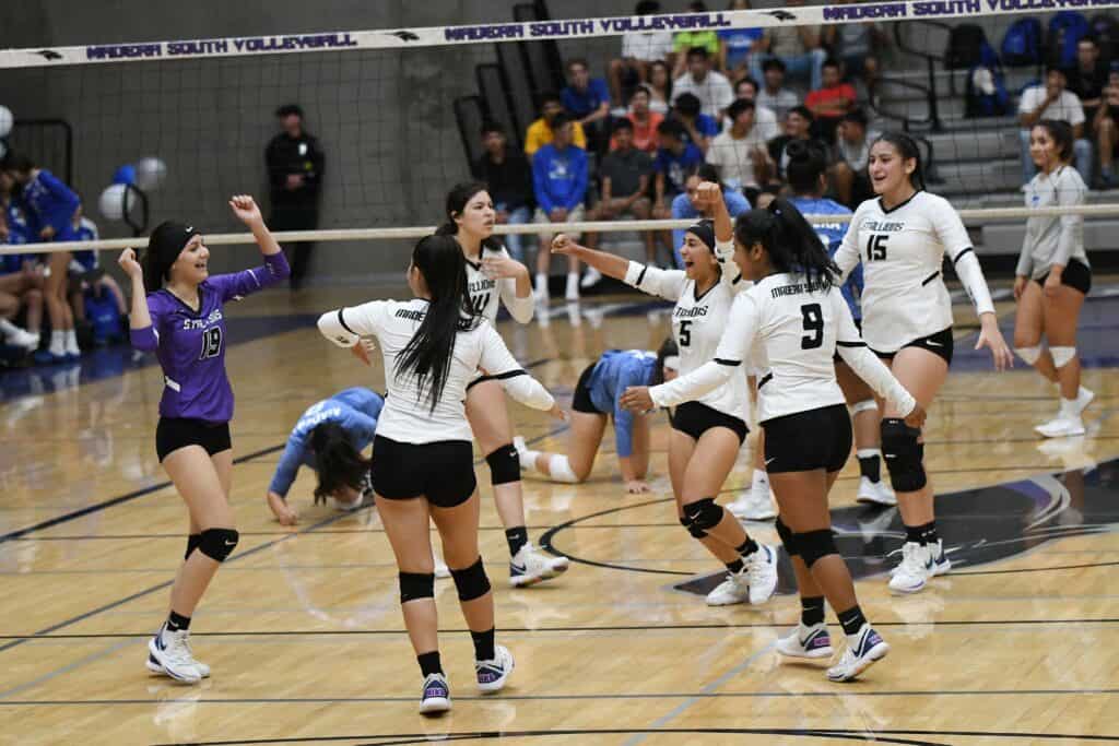 Madera volleyball team celebrating during a match in the gymnasium.