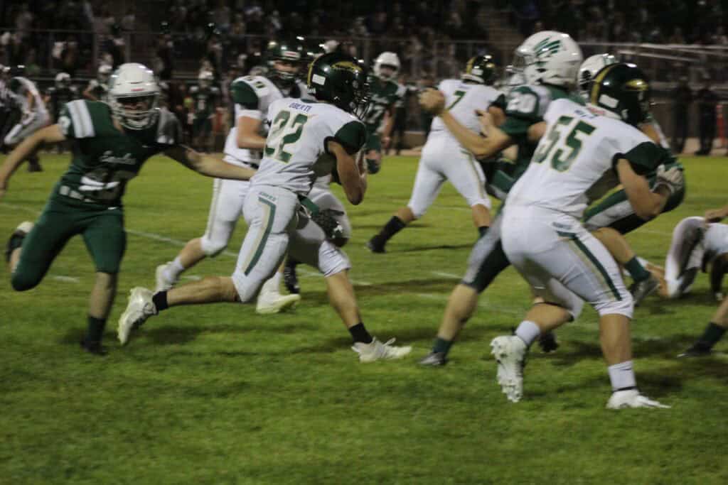 Madera football players in action during a game at night.