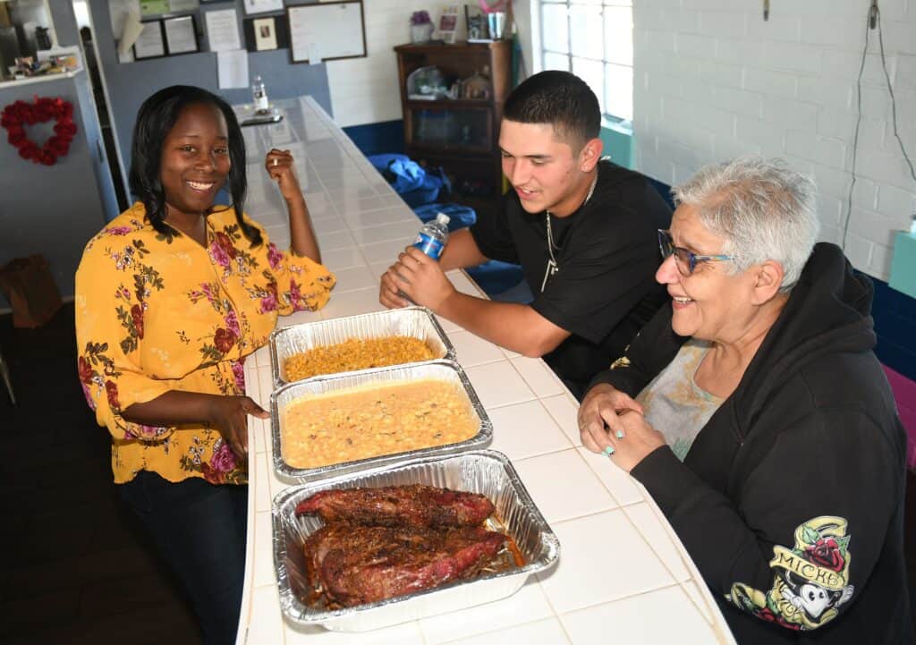 People enjoying a community meal with barbecue and sides at a local event.