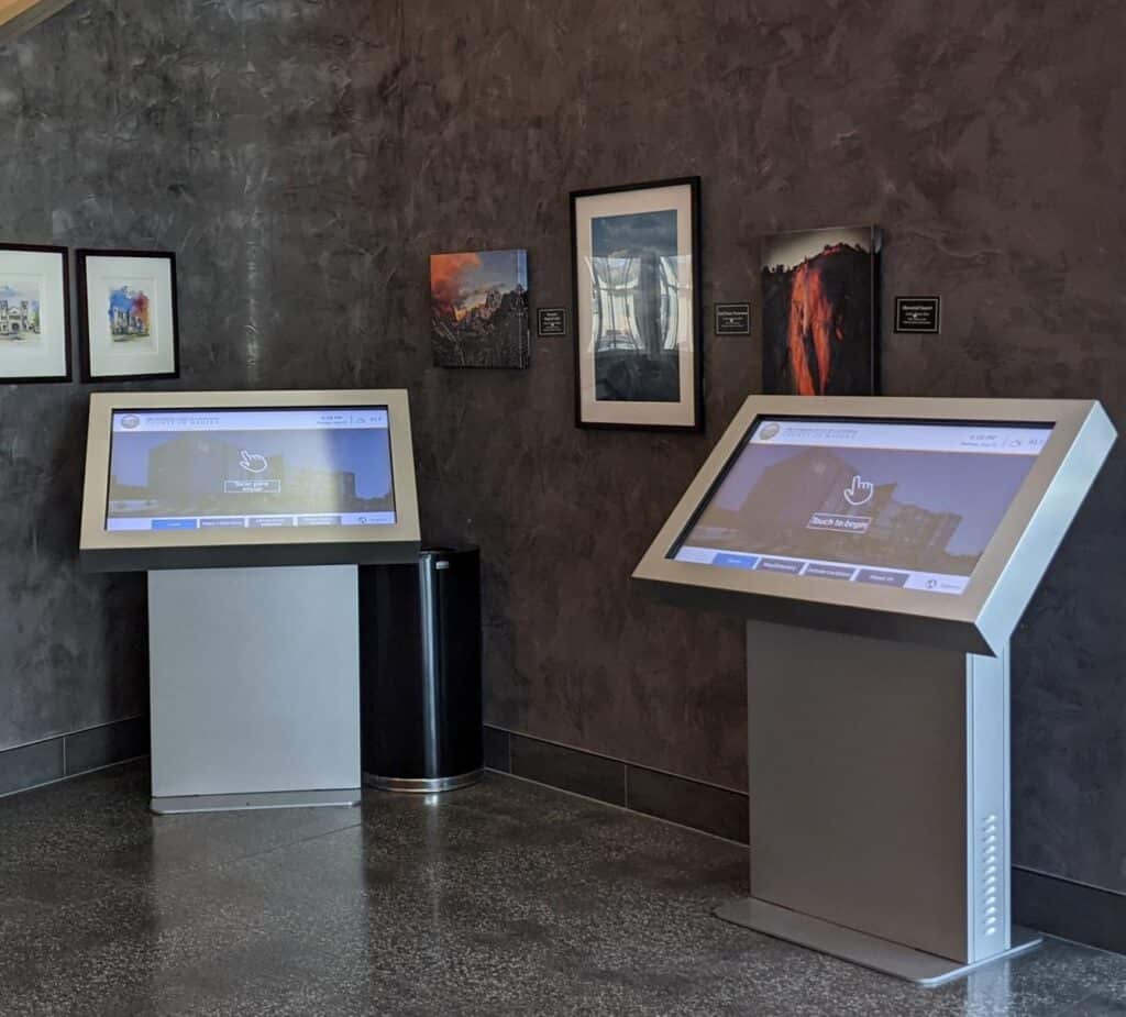 Modern digital kiosks at Madera Tribune exhibit in a gallery setting.