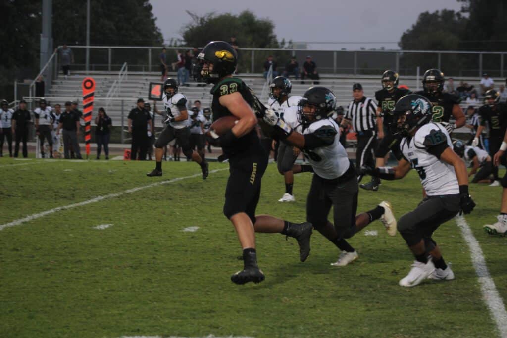 Madera football players in action during a game on the field.