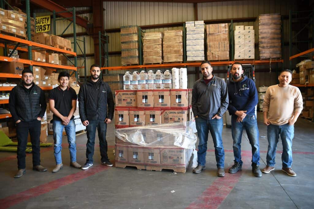 Warehouse team standing with supplies and water bottles.