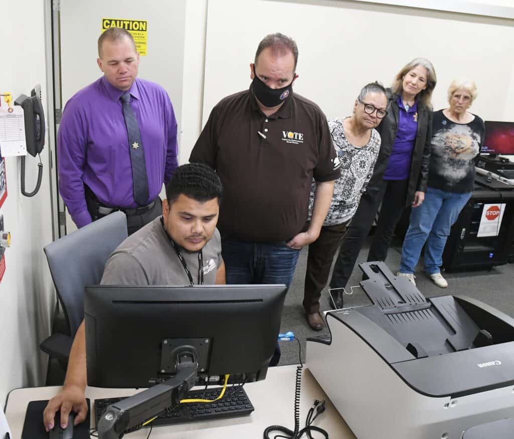 Group of voters and election officials at polling station during voting process.