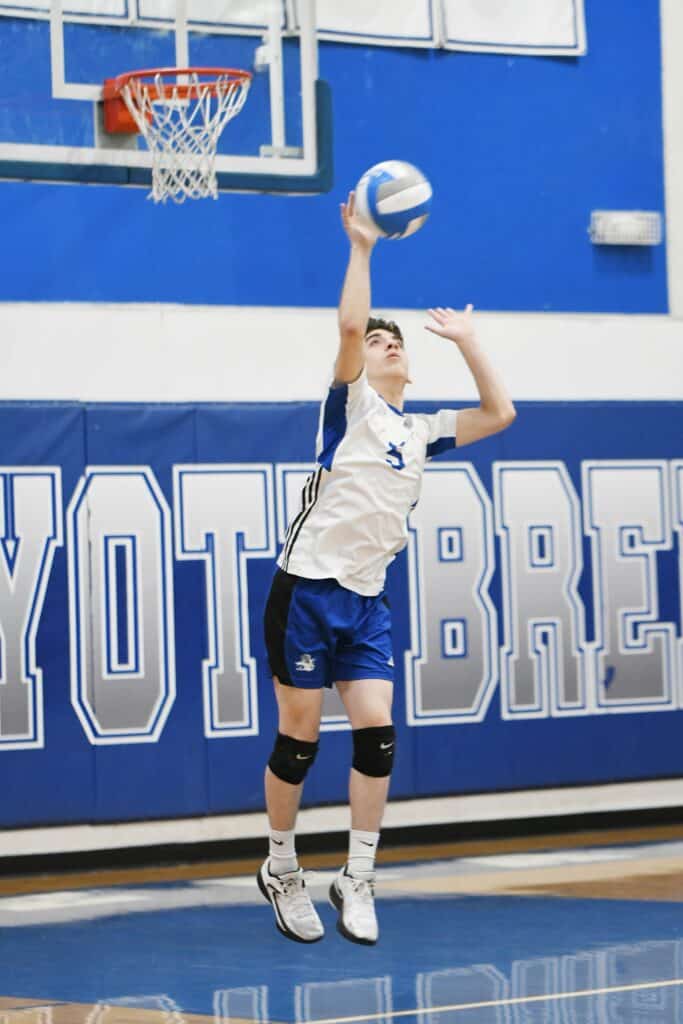 Young volleyball player jumping to spike the ball in gym.