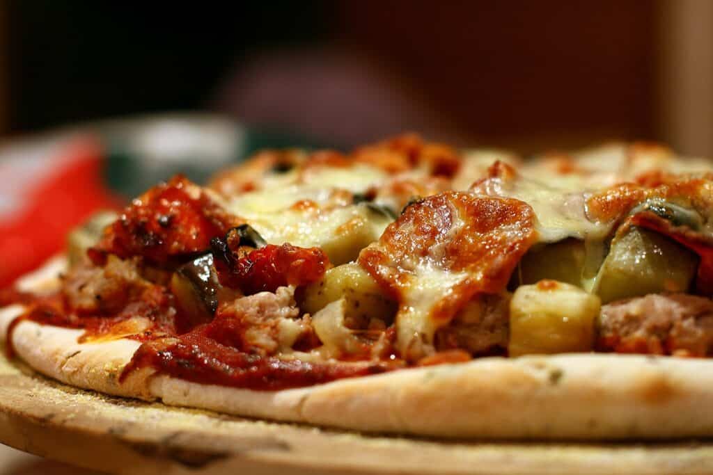 Close-up of a freshly baked meat and vegetable pizza with melted cheese.