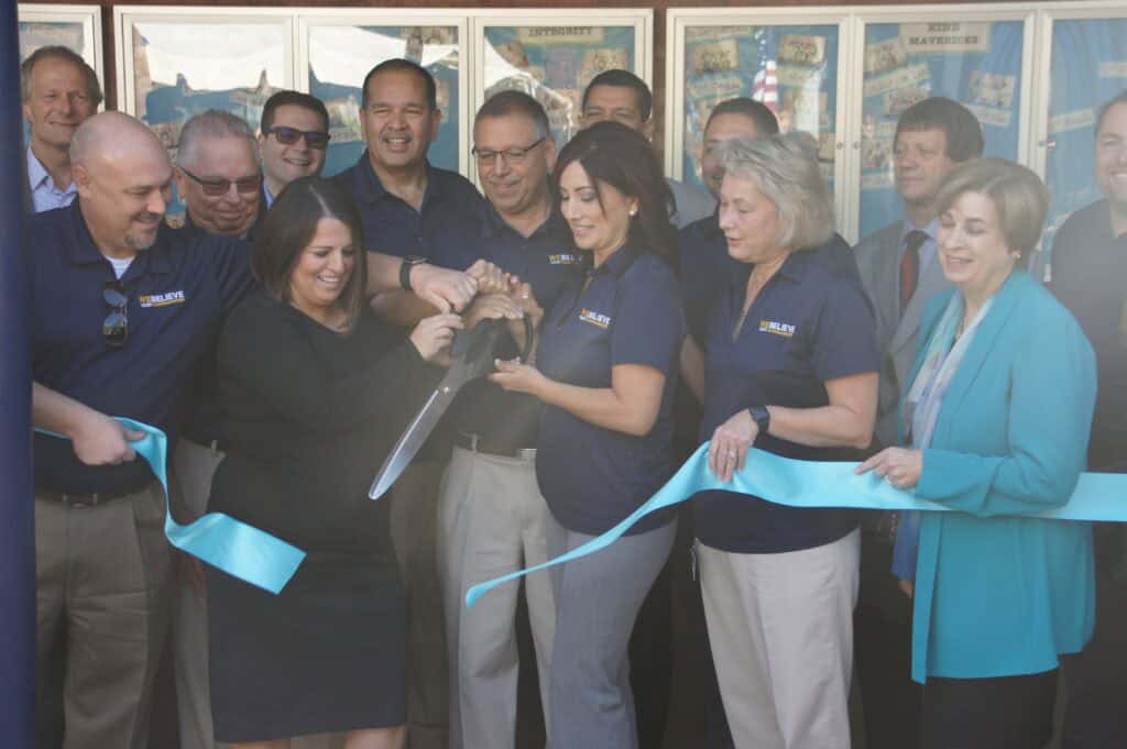 Group of people at ribbon-cutting event celebrating community news.