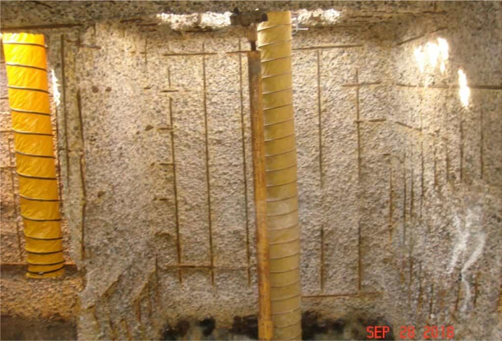 Construction site with concrete wall and yellow support beams.