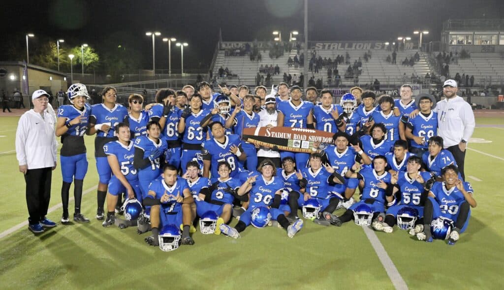 Madera High football team celebrating victory on the field at night.
