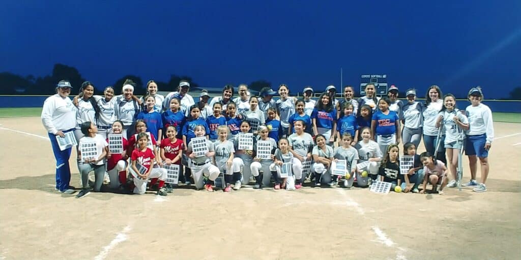 Softball team group photo on the field at night, celebrating their season success.