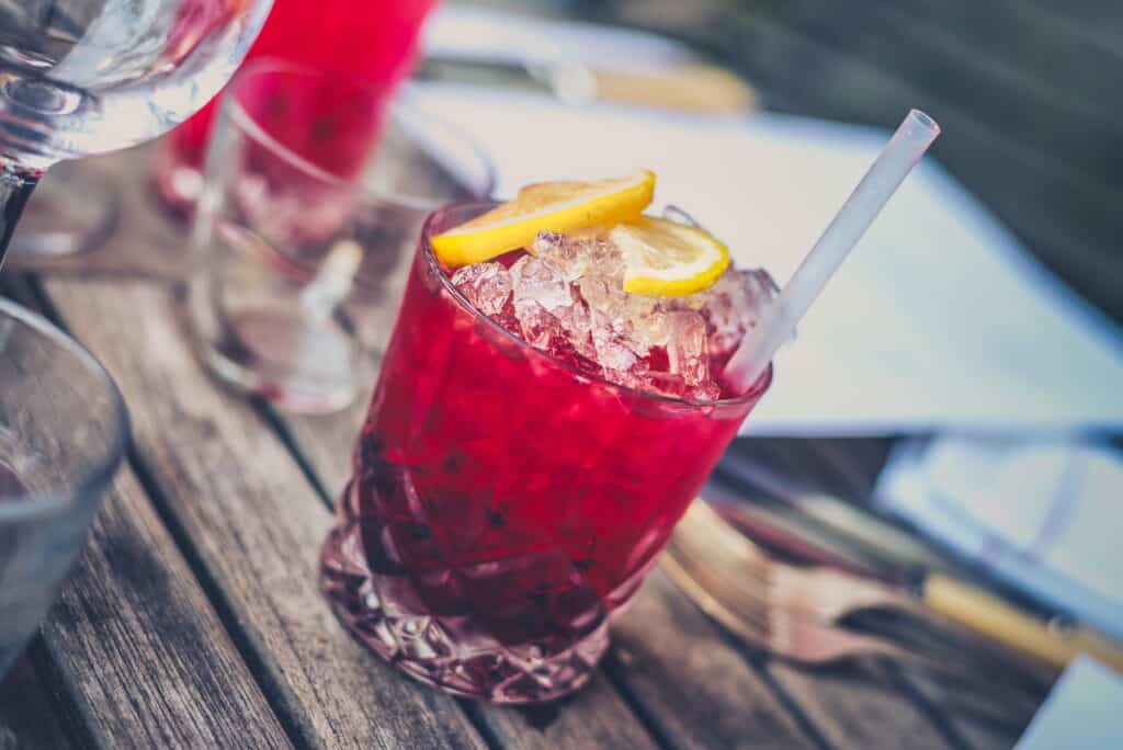 Bright red berry lemonade with lemon slices and ice in a glass.