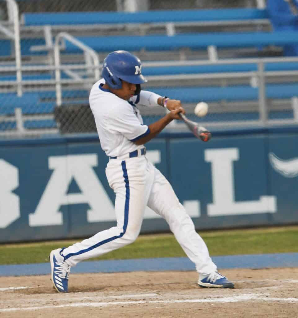 Baseball player swinging at a pitch during a game.